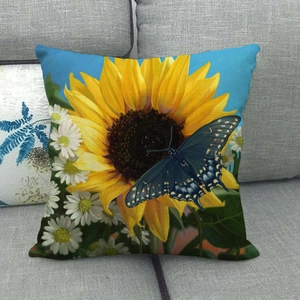 Dettaglio federa in lino con stampa girasole e farfalla su un divano grigio
