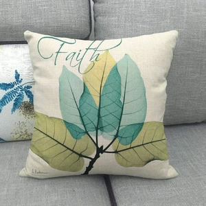 Close-up of linen pillow cover featuring green ink flower patterns and Faith text