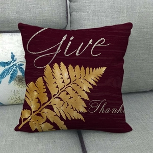 Detail of burgundy linen pillowcase with gold fern leaves and Give Thanks text