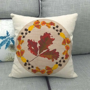 Close-up of autumn linen pillowcase with leaf wreath design on a grey sofa