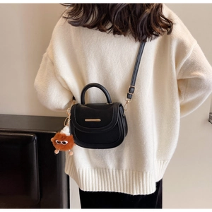 Détail du sac selle noir avec barre dorée et charmant pendentif monstre en peluche