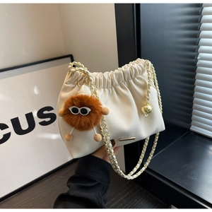 Detailed close-up of cream leather bucket bag with gold chain strap and fluffy charm
