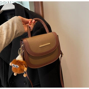 Détail d'un sac besace vintage avec garniture dorée et pendentif en peluche doux