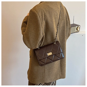 Detailansicht der dunkelbraunen Stepptasche mit goldenem Drehverschluss und Kette