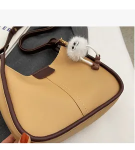 Detail of beige bucket bag with brown contrast trim and cute white plush eye charm