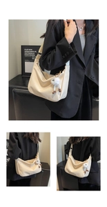 Detail of soft cream leather crossbody bag with fuzzy monster charm and wide strap