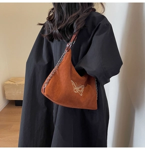 Detailed view of brown suede shoulder bag with butterfly embroidery and chain strap