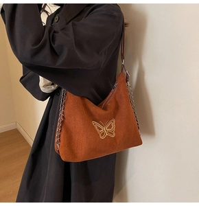 Detail of caramel suede tote with gold butterfly embroidery and silver chain strap