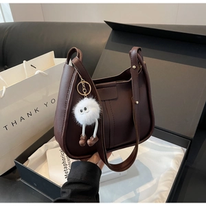 Detail of dark brown vintage leather bucket bag in a gift box with plush charm