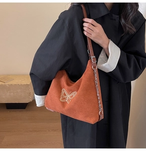 Detail of butterfly embroidery on brown suede tote bag with stylish chain leather strap