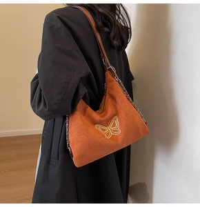 Detail of hobo bag with golden butterfly embroidery and metal chain leather strap