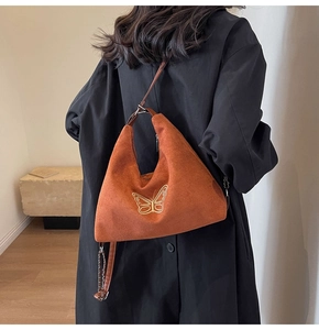 Detail of brown suede hobo bag featuring golden butterfly embroidery and leather strap