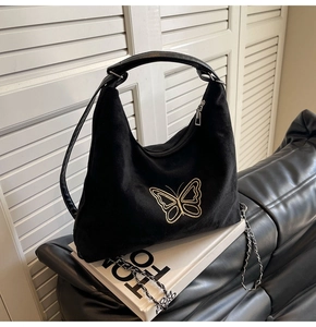 Detail of black corduroy hobo bag with gold butterfly embroidery and metal chain strap