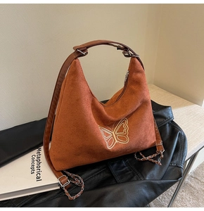 Detail of caramel suede bag with gold butterfly embroidery on a black leather jacket
