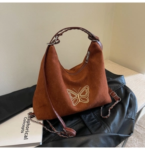 Detail of brown suede hobo bag featuring golden butterfly embroidery and chain strap