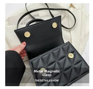 Detail view of the black quilted crossbody bag showing its golden magnetic snap closures