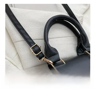 Detail view of gold metal adjustment buckle and black leather strap on a quilted handbag