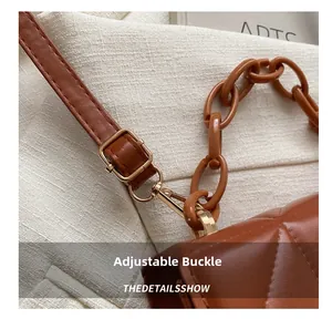 Détail de la boucle réglable et du fermoir mousqueton sur un sac matelassé marron
