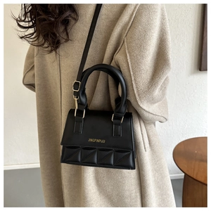 Détail d'un sac bandoulière matelassé noir en similicuir avec logo doré brillant
