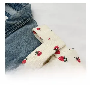 Close-up of white corduroy handbag with strawberry print and stitched handle detail