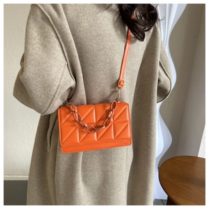 Détail du sac bandoulière matelassé orange avec chaîne en résine et bandoulière en cuir