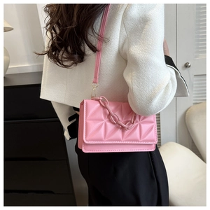 Sac à bandoulière rose matelassé avec grosse chaîne porté par un mannequin en veste tweed