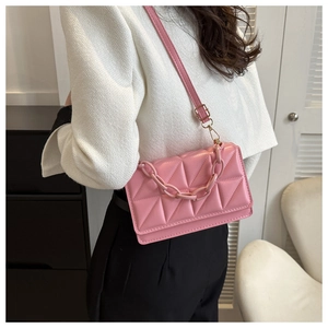 Détail montrant la texture matelassée rose et la chaîne décorative du sac à bandoulière