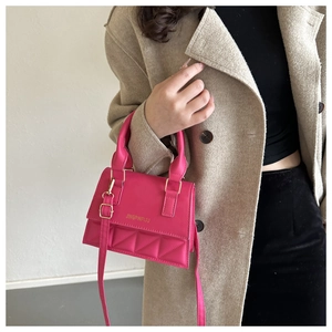 Détail du sac à main rose avec matelassage en losanges et finitions dorées sur manteau