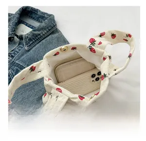 Detailed interior of corduroy strawberry handbag showing capacity for phone and wallet