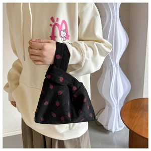 Détail d'un sac à nœud en velours côtelé noir avec des fraises rouges et texture