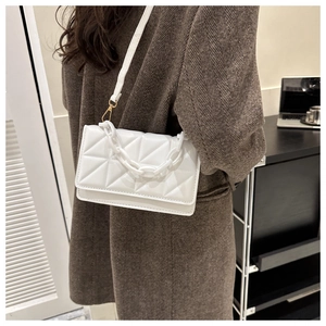 Vue détaillée du sac bandoulière blanc matelassé avec chaîne épaisse et détails dorés