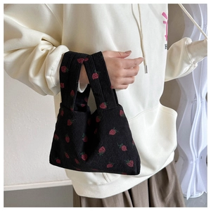 Gros plan d'un sac à main en velours côtelé noir avec motifs fraises vintage et texture