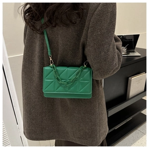 Petit sac bandoulière matelassé vert avec chaîne décorative porté par un mannequin