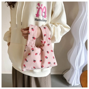 Détail du sac à main en velours côtelé rose avec motif fraise et les anses