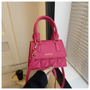 Detail of rose red structured crossbody bag featuring quilted patterns and gold hardware