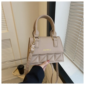 Close-up of matte leather handbag featuring geometric quilted stitching and top handle