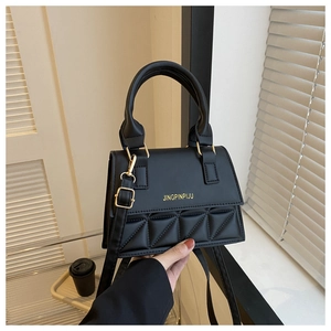 Detail of black triangular quilted crossbody bag with gold hardware on white background