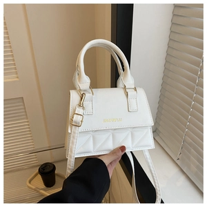 Detail of white quilted crossbody bag with golden hardware and round top handle