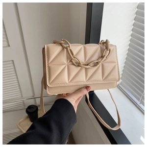 Détail du sac beige matelassé avec chaîne en résine et texture cuir raffinée
