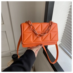 Détail du sac bandoulière orange en cuir matelassé avec poignée chaîne et bandoulière