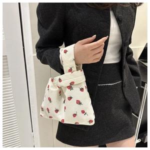 Détail d'un mini sac à main en velours côtelé crème avec imprimés fraises et anse nouée