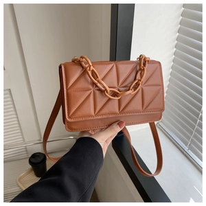 Détail du sac matelassé marron caramel avec chaîne en résine et bandoulière en cuir