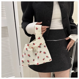 Détail du sac à poignet en velours côtelé blanc avec motif fraise rouge et texture
