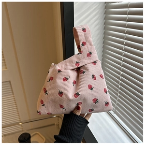 Détail du sac à main en velours côtelé rose avec imprimé fraises et poignée nouée