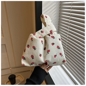 Gros plan du sac à nœud en velours côtelé imprimé fraises avec texture douce et dragonne