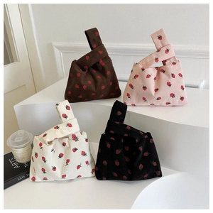Corduroy mini strawberry wrist bags in brown, pink, white, and black on a white display