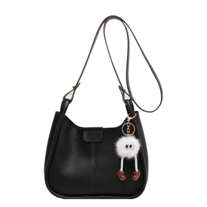 Retro black matte leather saddle shoulder bag featuring a cute furry monster charm pendant