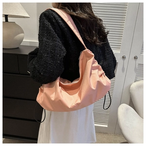 Detailed side view of coral pink canvas crossbody cloud bag with adjustable drawstrings