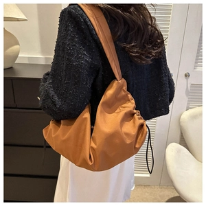 Caramel pleated cloud shoulder bag styled with a black tweed jacket for a chic look