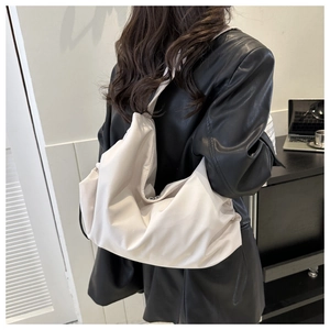 Detail of white slouchy shoulder bag in soft synthetic fiber on a person wearing leather jacket
